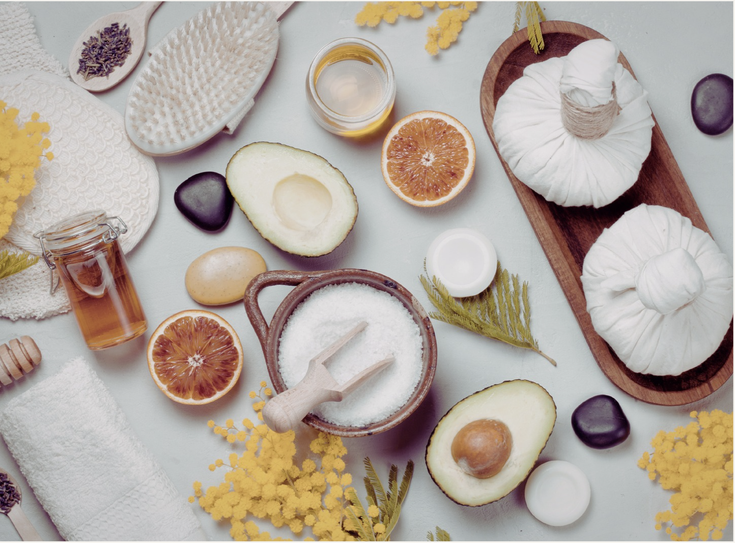 Flatlay of natural skincare ingredients: citrus, avocado, honey, salt, lavender and herbal compresses
